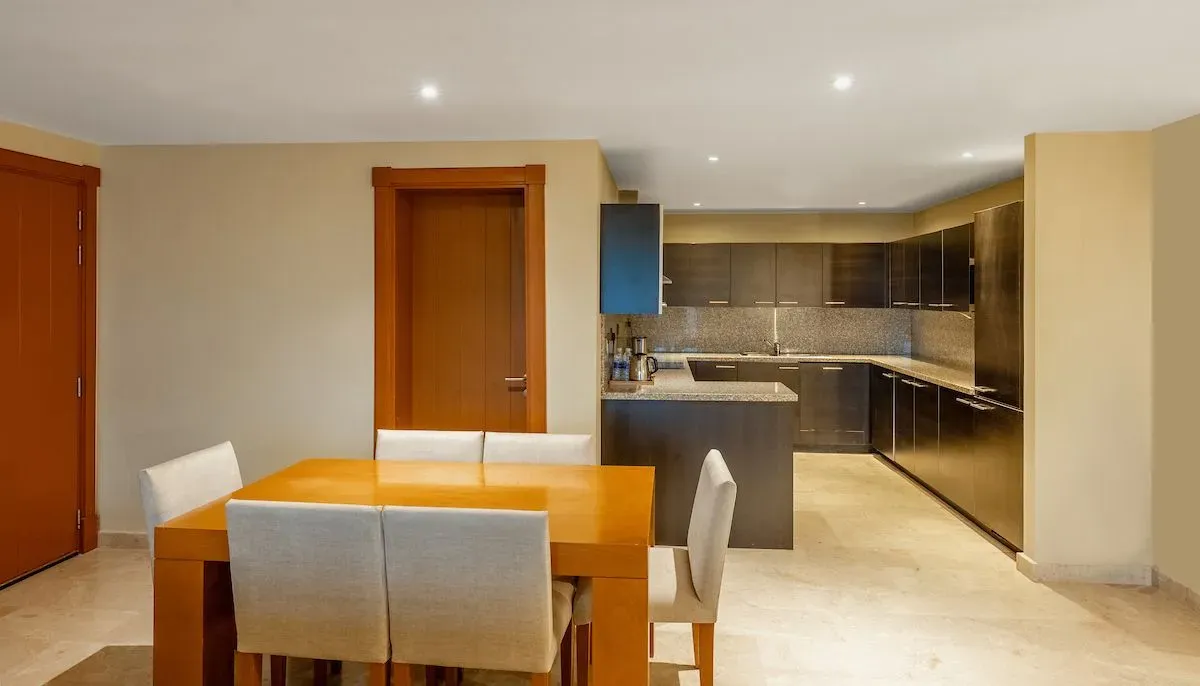 Two-bedroom apartment interior featuring a modern kitchen and dining table with chairs.