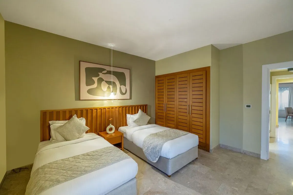 A modern two-bedroom apartment featuring two twin beds, wooden paneling, and soft lighting.
