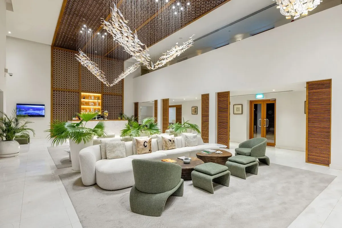 Stylish hotel lobby with modern furniture, lush plants, and an intricate ceiling design.